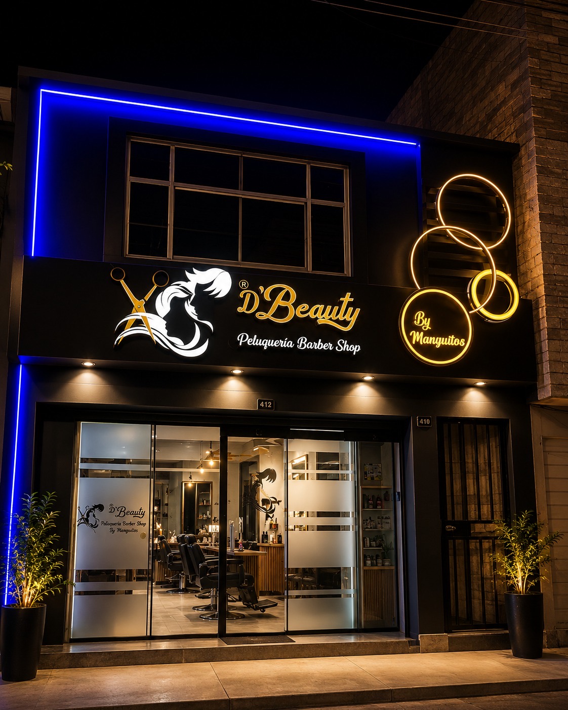 Fachada real de D'Beauty Peluquería Barber Shop con neón azul, logo iluminado y aros decorativos.